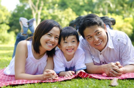 Outdoor happy Asian family lying on floor