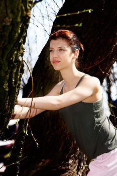 Jogging teenage girl stretching using tree