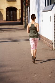 Teenage girl jogging away on sidewalk in city