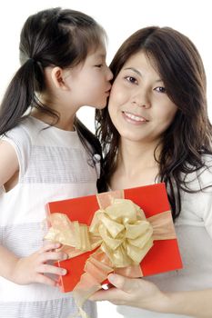 Little Asian girl giving gift for mother and kissing on mother's cheek