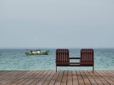 Two empty chair at a resort facing the south China sea in Pulau Besar Malaysia with a boat in the background