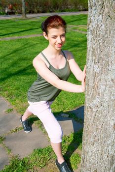 Teenage girl stretching in park in spring, smiling