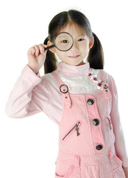 A little girl peers at the camera through a magnifying glass.