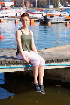 Teenage girl sitting in harbor, looking at camera