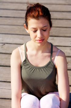 Peaceful teenage girl meditating on pier outdoors
