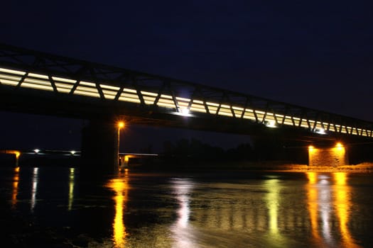 Illuminated railway bridge over the Elbe in Dessau - Rosslau, in Saxony-Anhalt / Germany, with a moving train