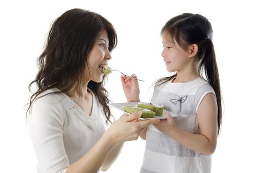 Little Asian girl feeding cake for her mother
