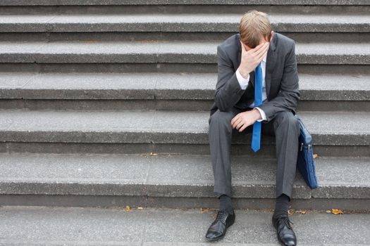 A worried business man sitting on some stairs