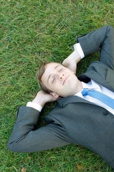 A business man lying on the grass