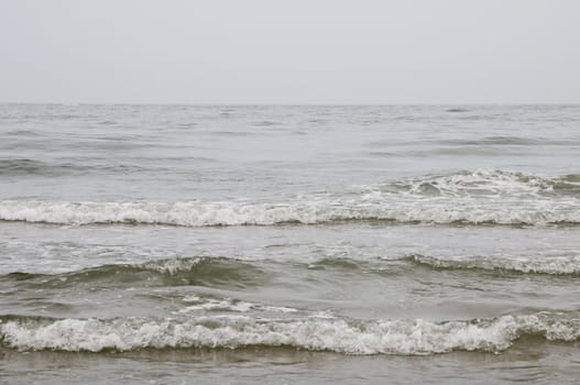 A gray seascape with a waves on against the gray sky