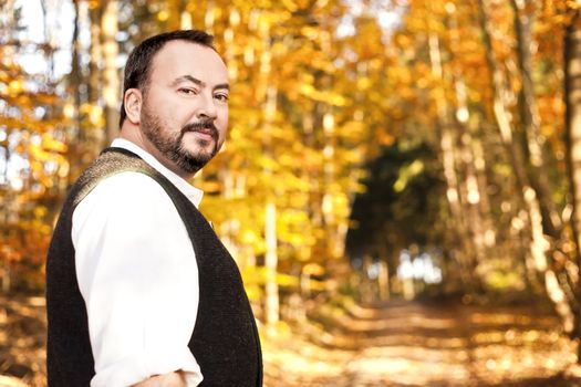 A handsome man with a beard in the autumn forest