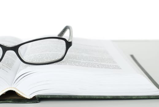 Glasses on open book on white background