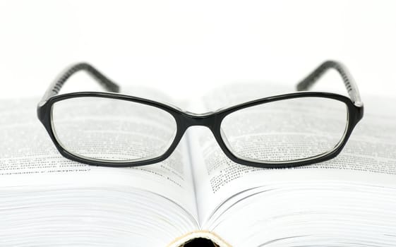 Glasses on open book on white background