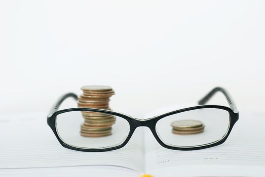 Glasses, books and piles of coins