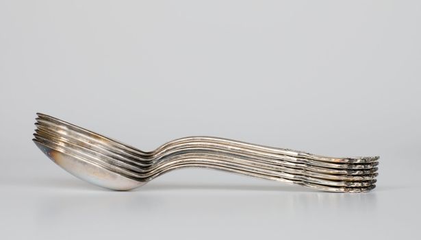 Old silver spoons on grey background