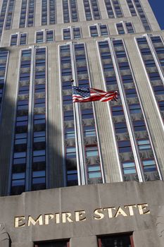 New York City, New York, USA - October 7, 2010: American flag blowing in the wind in front of the Empire State Building on 5th Ave., Manhattan.