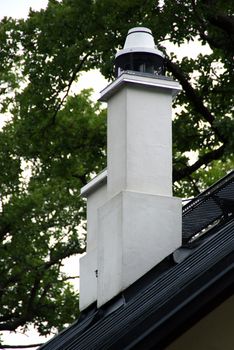 White chimney is located on a background of green tree