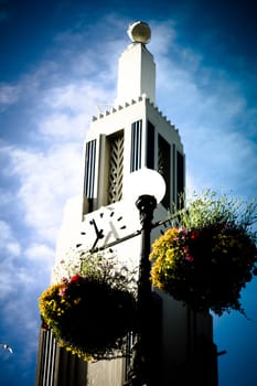 time tower and flowerpots in azure sky with white clouds