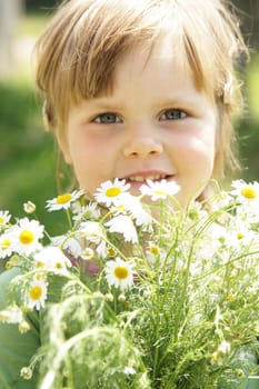 Little girl with daisies outdoor on sunny day