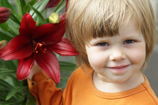 Little girl with a red lily in the garden