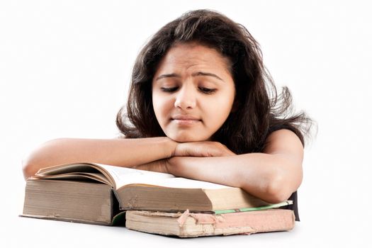 Tired and exhausted Young indian girl leaned over pile of  old books, isolated on white