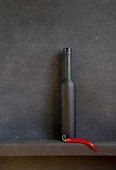 black still-life with bottle and red pepper