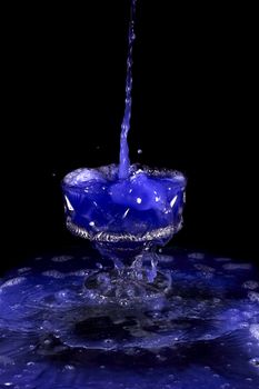 a crystal vase with blue liquid on the black background