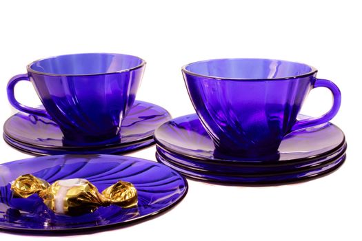 two blue cups with saucers and a sweet on the white background