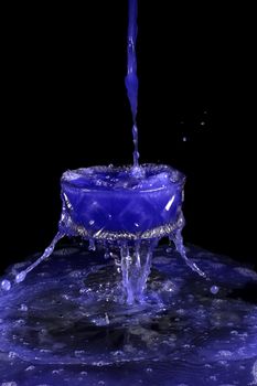 a crystal vase with blue liquid on the black background