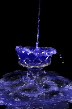 a crystal vase with blue liquid on the black background