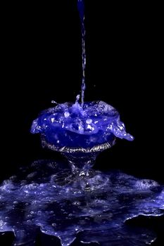 a crystal vase with blue liquid on the black background