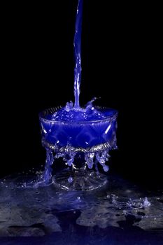 a crystal vase with blue liquid on the black background