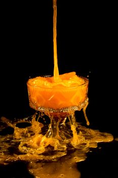 a crystal vase with orange liquid on the black background
