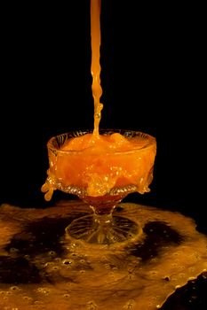 a crystal vase with orange liquid on the black background
