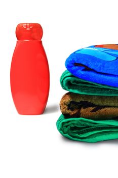 a bottle of shampoo and a pile of towels on the white background