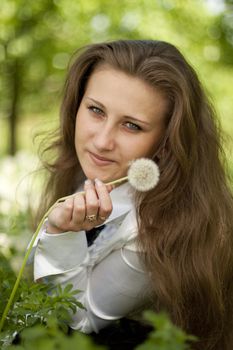 girl holding a dandelion looking at Lens