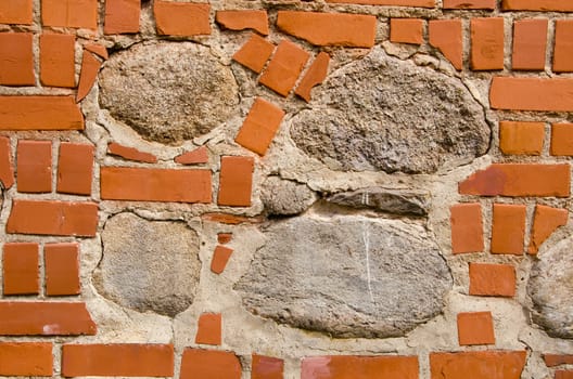 Intresting old wall fragmentmade of red bricks and stones. Architectural background.