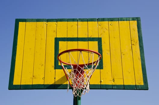 Basketball board painted green and yellow with net on the hoop.