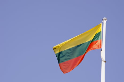 Lithuanian tricolor flag flies in the wind. Yellow green red.