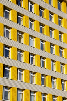 Fragment of yellow tall building with many windows.