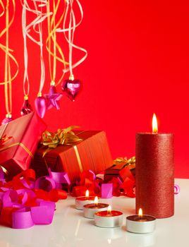 Christmas gifts and candles over red background