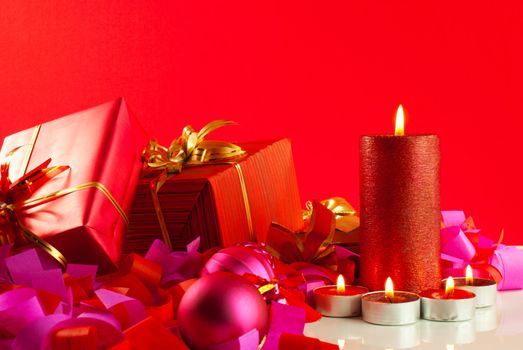 Christmas gifts and candles over red background