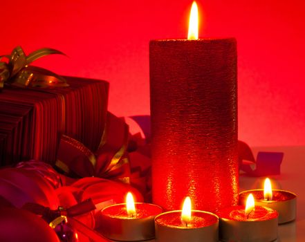 Candles and gifts over red background