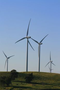 Close up of wind turbines over blue sky.
