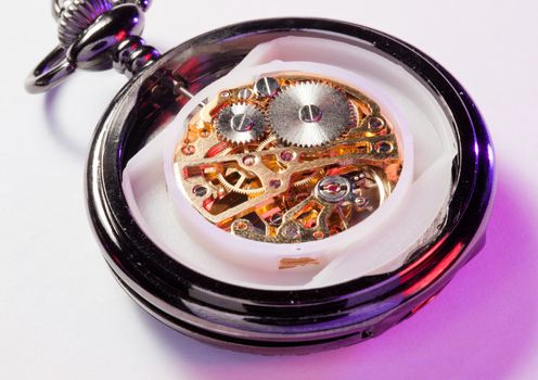 Color lights illuminate an old pocket watch with the mechanism