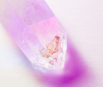 Different color lights illuminate a shaped quartz crystal showing the facets and marks