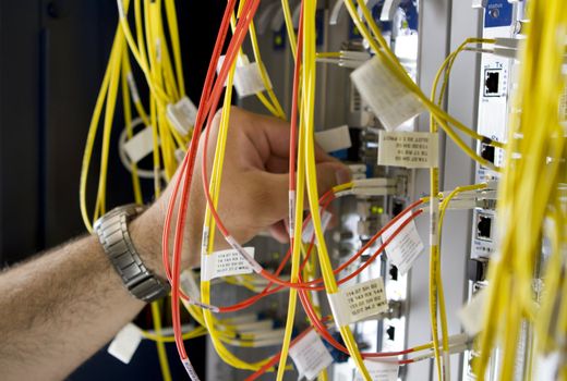 Carefull hands connecting Telecommunications equipment fiber optic cables.