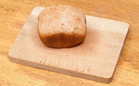 Whole wheat loaf from a bread making machine ready to cut on cutting board
