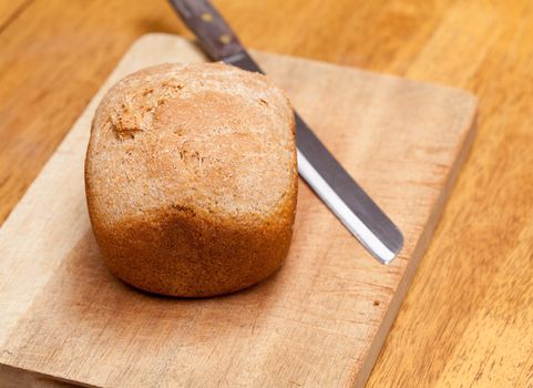 Whole wheat loaf from a bread making machine ready to cut on cutting board