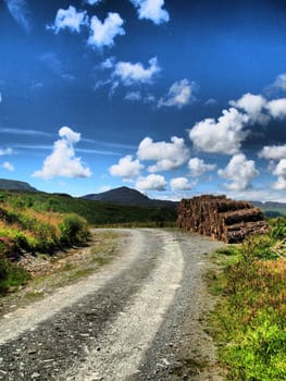 A gravel road curving off into the distance under a blue sky full with fluffy clouds